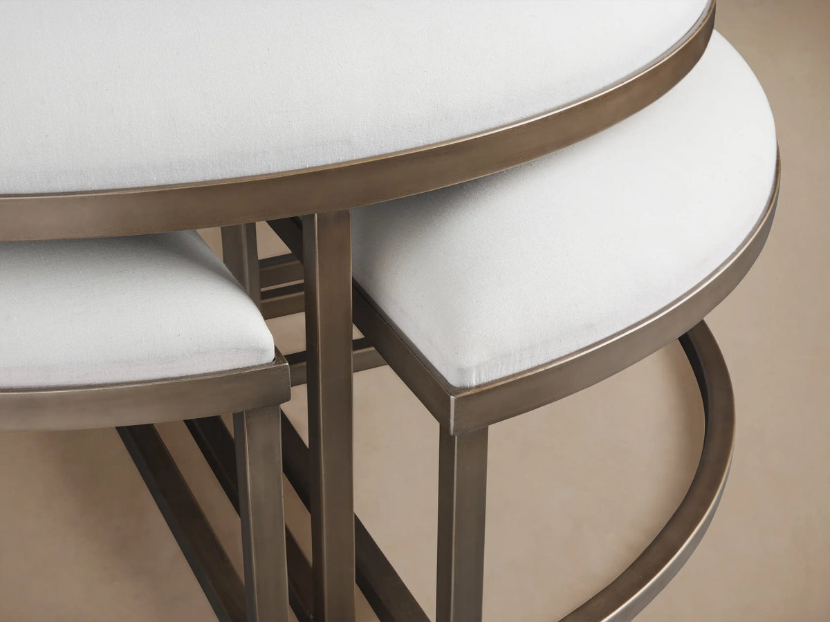 Palmer Upholstered Round Nesting Ottoman: large white cushioned round ottoman with two smaller crescent ottomans nested on wood floor.