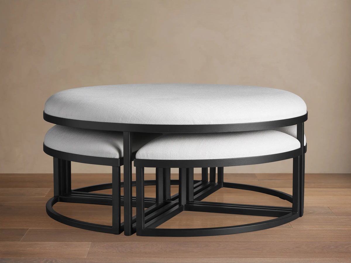 Palmer Round Nesting Ottoman set: large light grey upholstered main piece with four smaller ottomans nested inside, black metal.