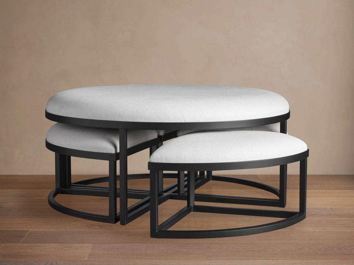 Palmer Round Nesting Ottoman set: large light grey upholstered main piece with four smaller ottomans nested inside, black metal.