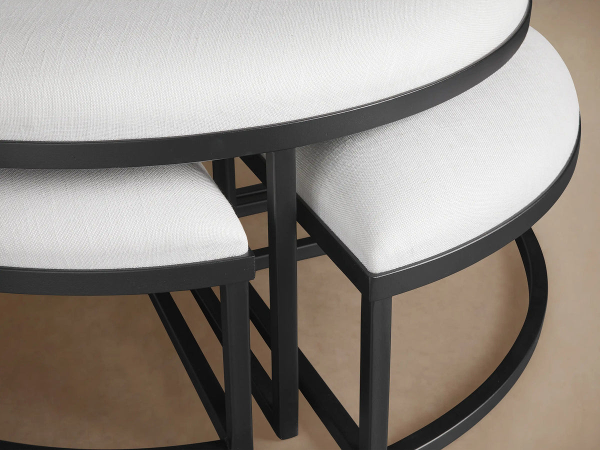 Palmer Upholstered Round Nesting Ottoman set. Light grey fabric tops, black metal frames. One crescent piece extended.