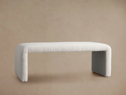 Ryan Bench in light fabric, features a modern design with rounded edges. Positioned on a wood floor against a neutral wall.