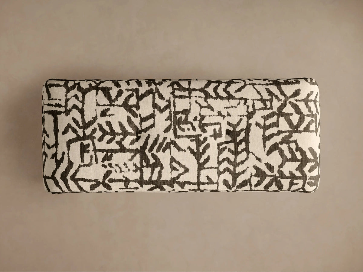 Close-up of Ryan Bench, upholstered in off-white fabric with striking dark abstract patterns, showing its curved corner.