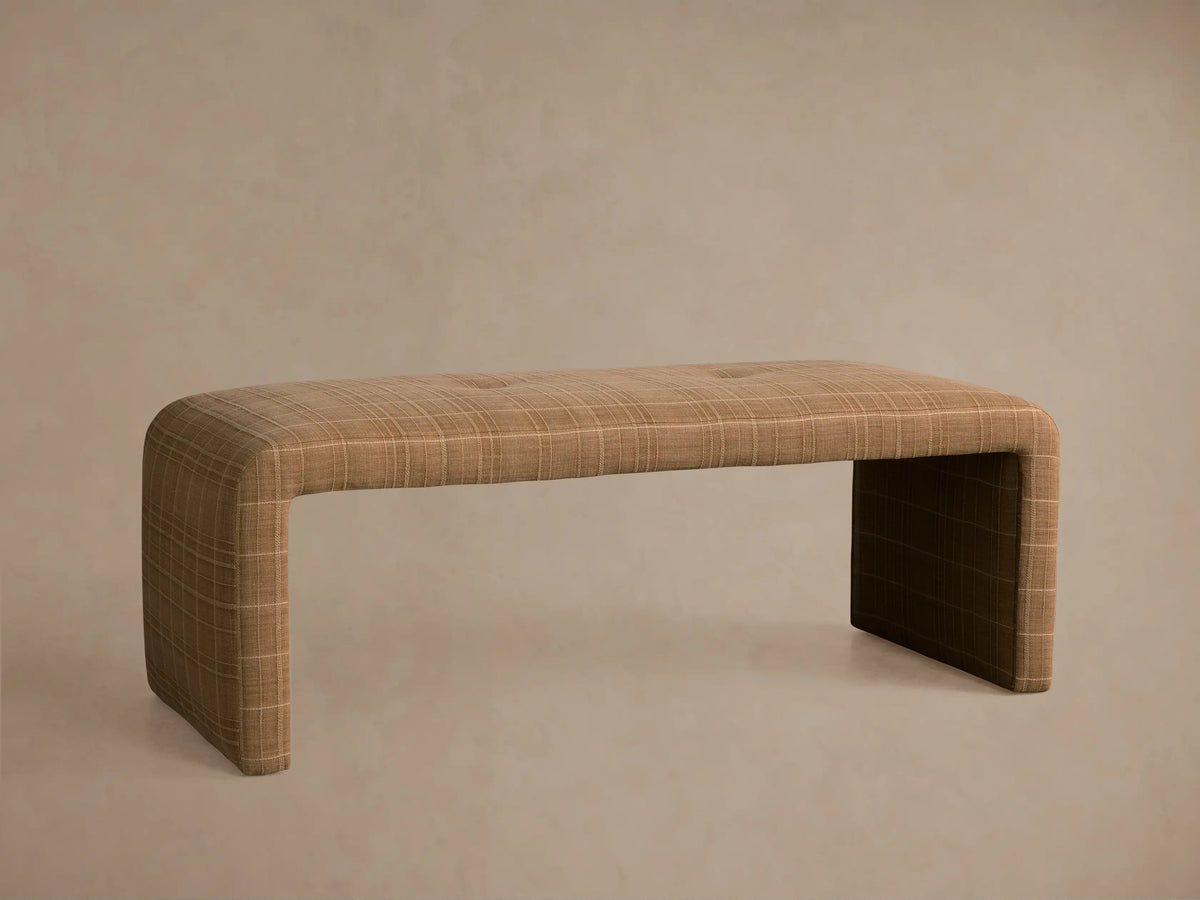 Ryan Bench, upholstered in light brown plaid fabric, angled view. Features a single tufted button and seamless waterfall design.