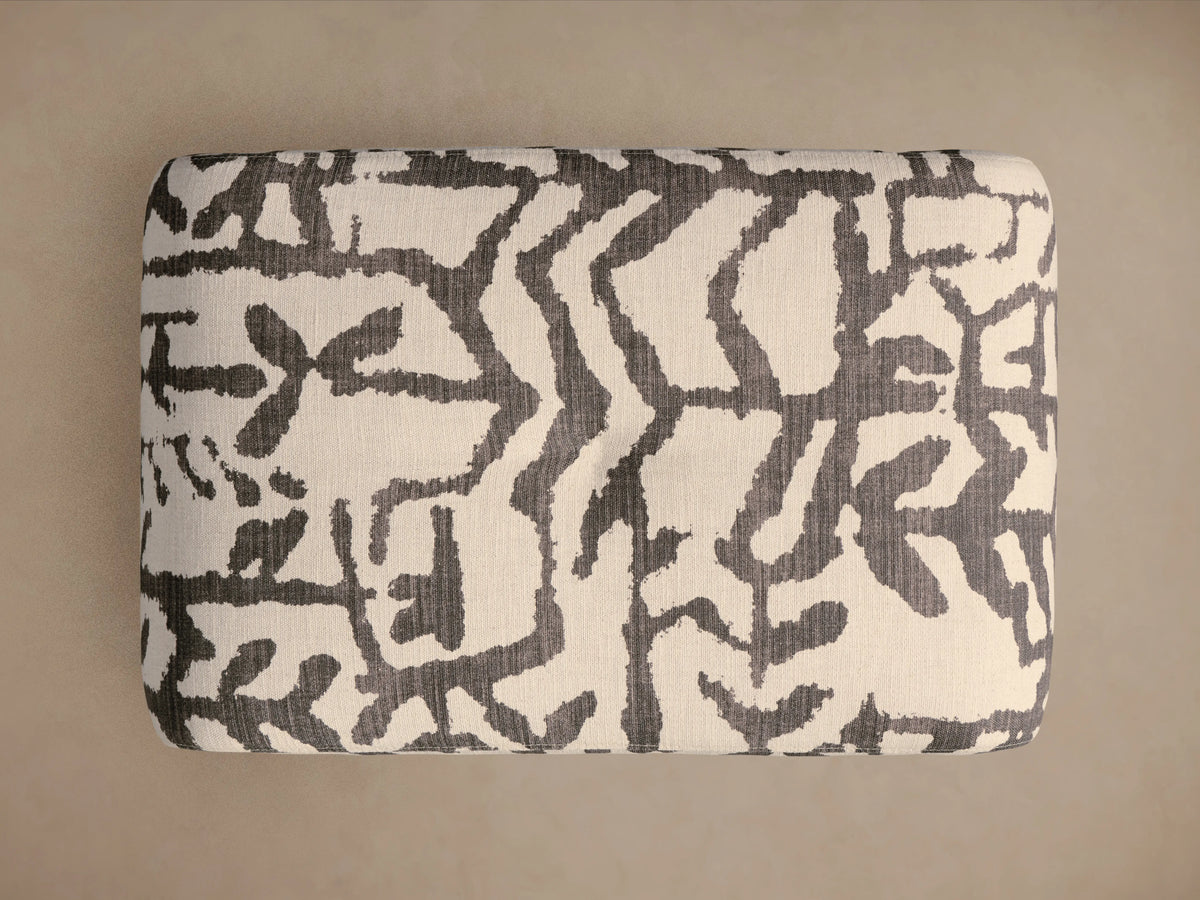 Close-up of Ryan Petite Ottoman upholstered in an off-white and dark grey abstract pattern, showing a rounded corner and fabric texture.