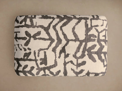 Close-up of Ryan Petite Ottoman upholstered in an off-white and dark grey abstract pattern, showing a rounded corner and fabric texture.