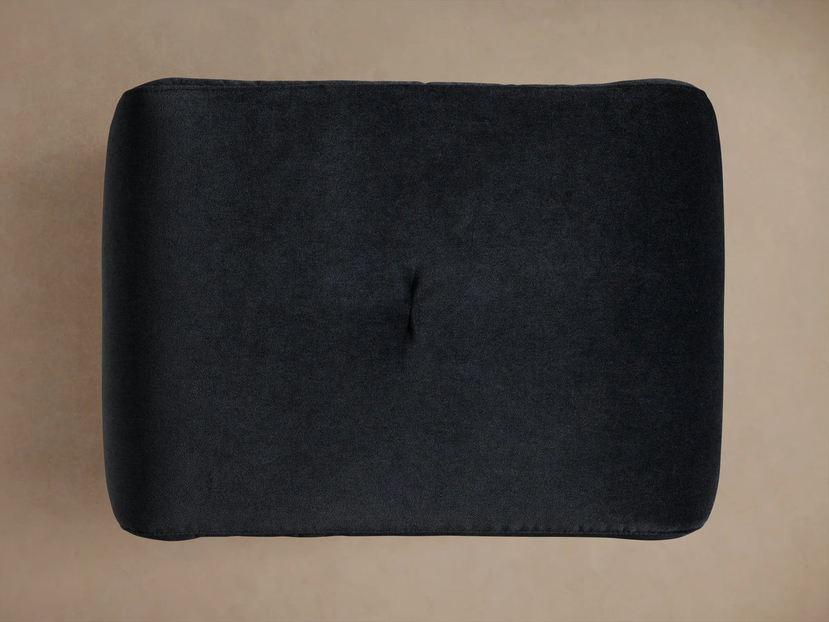 Ryan Mini Ottoman in dark charcoal fabric with a soft, velvety texture. The top has a single button tuft in the center.