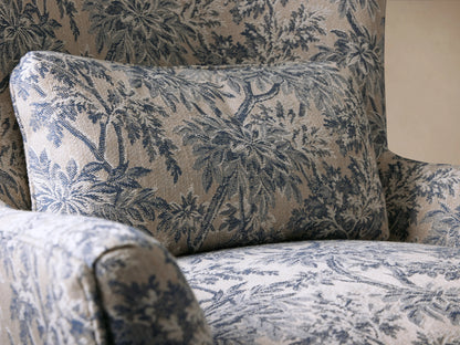 Rio Chair with high-back design in floral-patterned fabric, featuring wood legs with antique brass caster wheels, set on wooden floor.