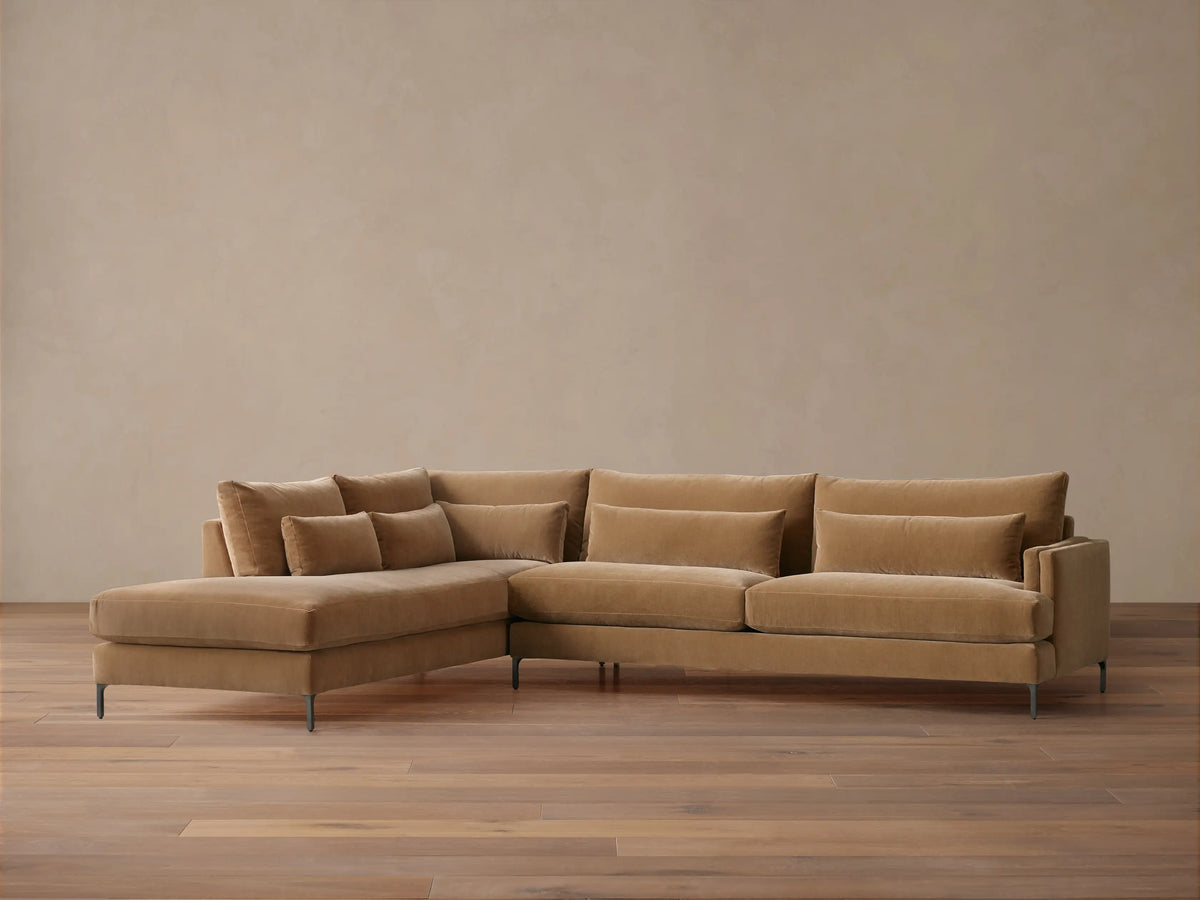 Sumner Two-Piece Bumper Sectional in light brown fabric, left chaise, three back cushions, two lumbar pillows, wooden floor, neutral wall.