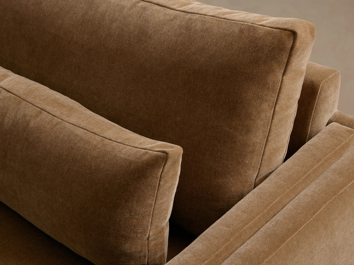 Sumner Two-Piece Bumper Sectional in tan fabric with a left-facing chaise. Features plush seat cushions, backrests, and a sleek design.