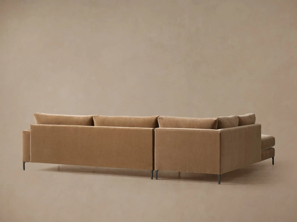 Sumner Two-Piece Bumper Sectional in soft brown fabric, featuring plush cushions, detailed seams, and a lumbar toss pillow.