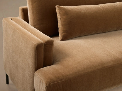 Front view of a warm brown velvet sofa with three back cushions, two lumbar pillows, and low square arms on dark legs.