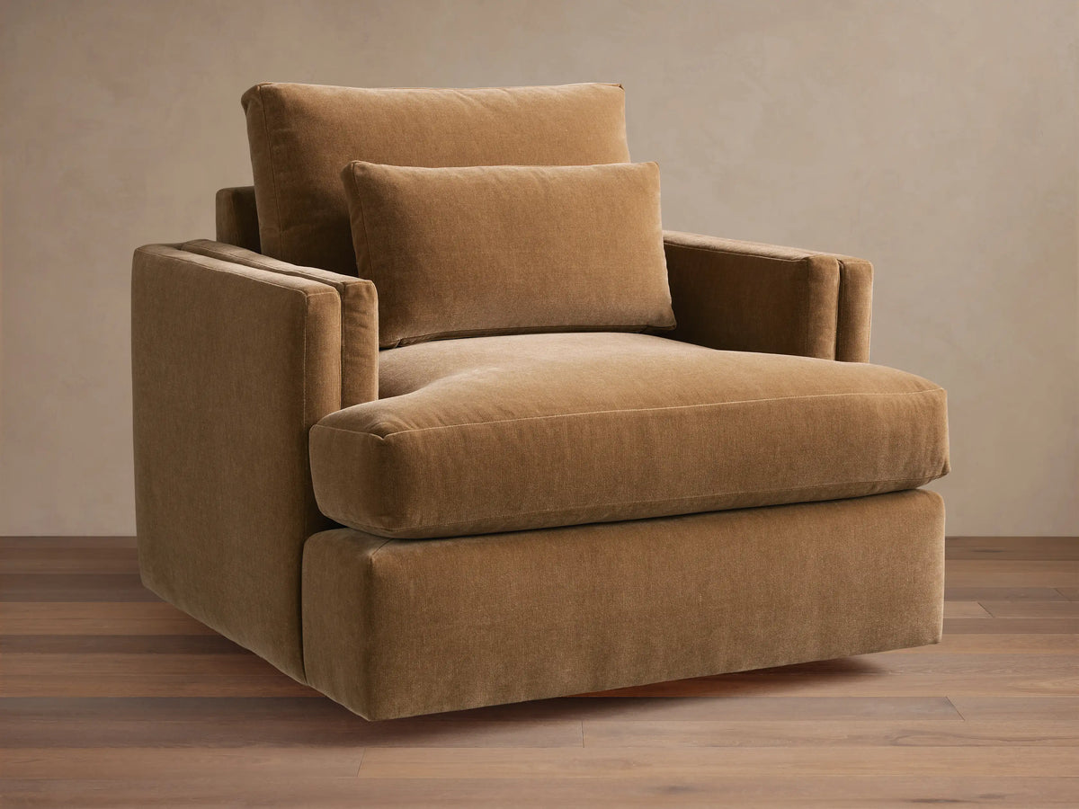 Sumner Swivel Chair in brown fabric, featuring a plush seat cushion, two padded back cushions, and solid square armrests on a hardwood floor.
