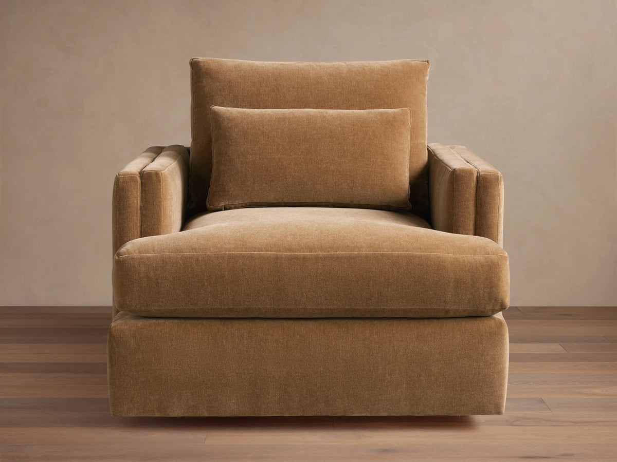 Sumner Swivel Chair in brown fabric, featuring a plush seat cushion, two padded back cushions, and solid square armrests on a hardwood floor.