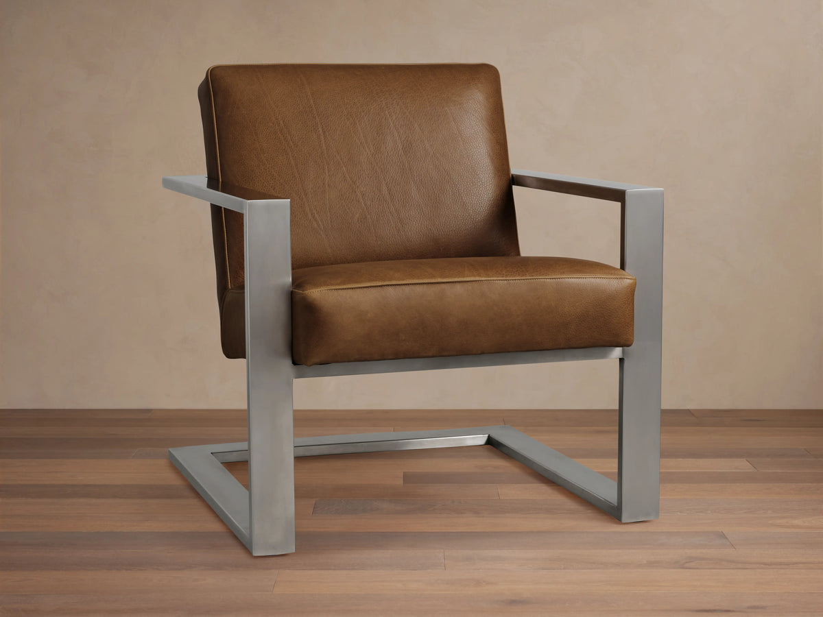 Front view of the brown Sabina Leather Chair, with rich brown leather cushions and a brushed silver-toned steel frame.