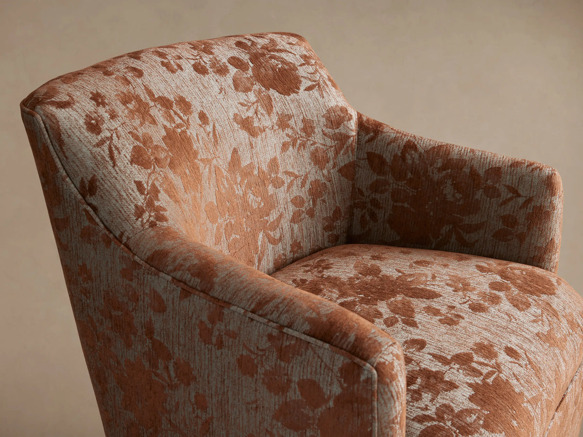 Savannah Chair: Upholstered armchair with a terracotta floral pattern on light grey fabric, dark wood legs, on a wooden floor.