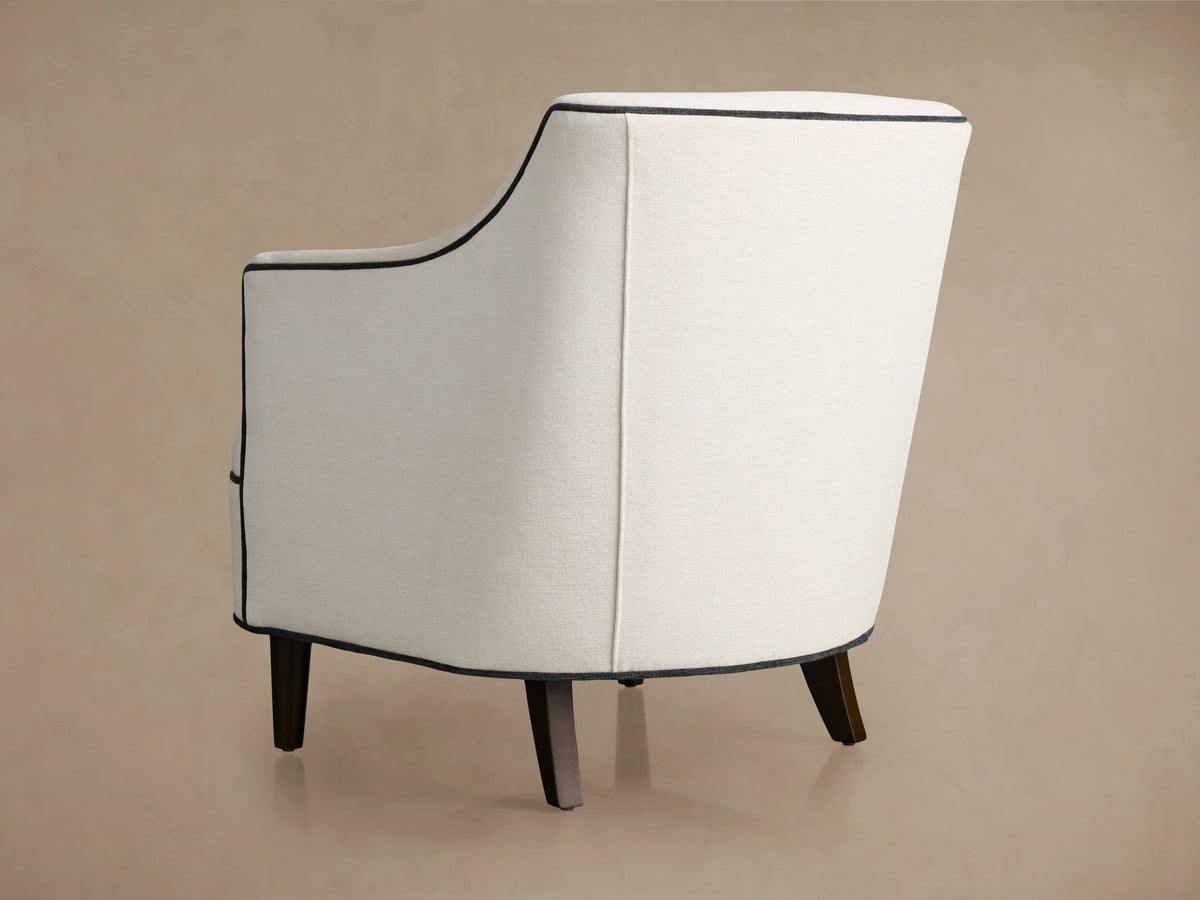 Savannah Chair, off-white upholstered fabric with black piping detail, viewed from top angle, showing seat and armrests.