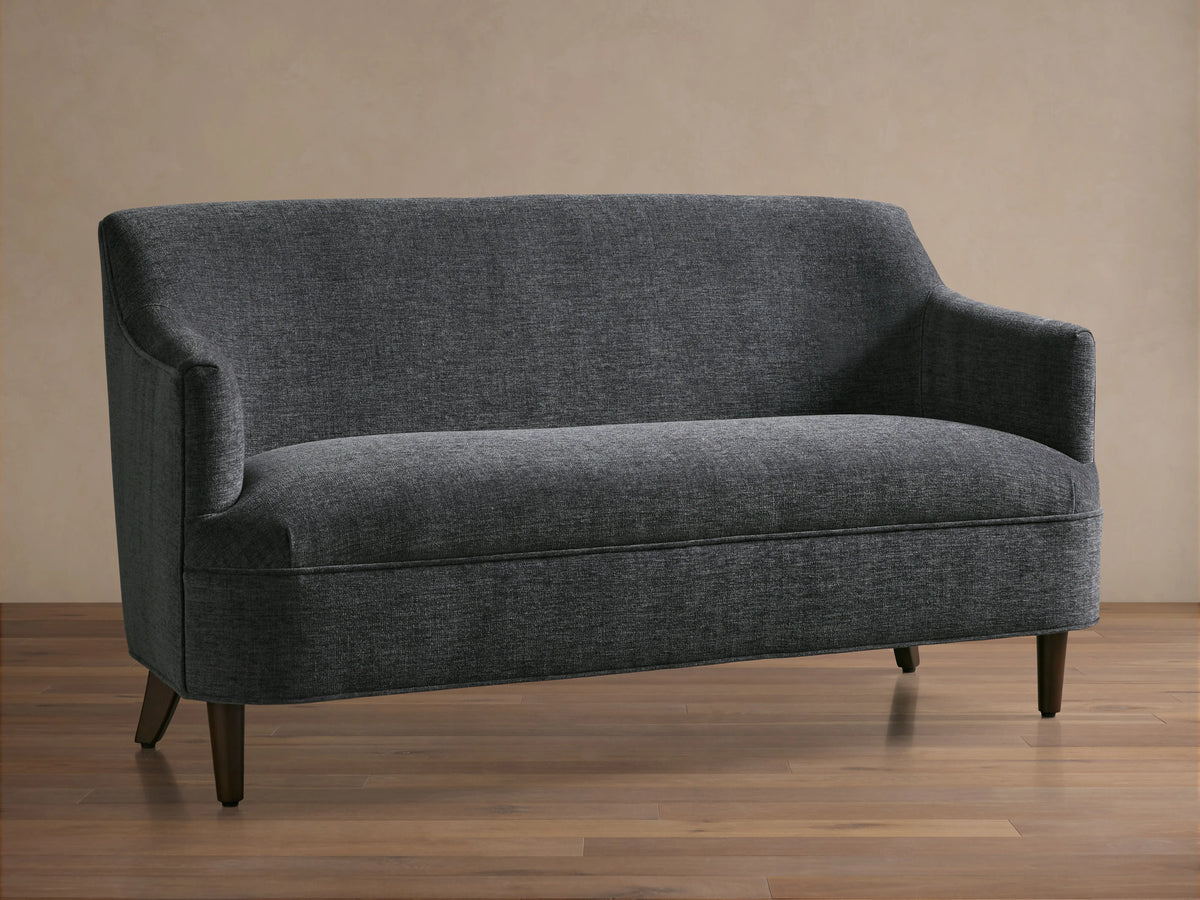 Savannah Settee: Dark gray textured fabric settee with a curved back and arms, on dark wooden tapered legs.