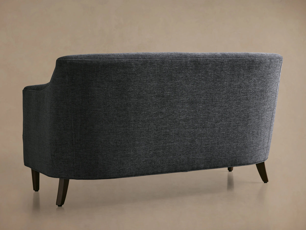 Savannah Settee, angled view from back-left, dark grey textured fabric, curved back and arm, with dark wood legs.