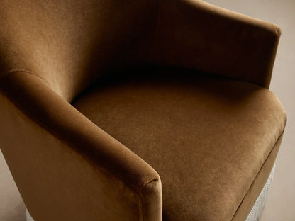 Warm brown Savannah chair with curved back and cream fringe skirt, angled slightly right on a wood floor.