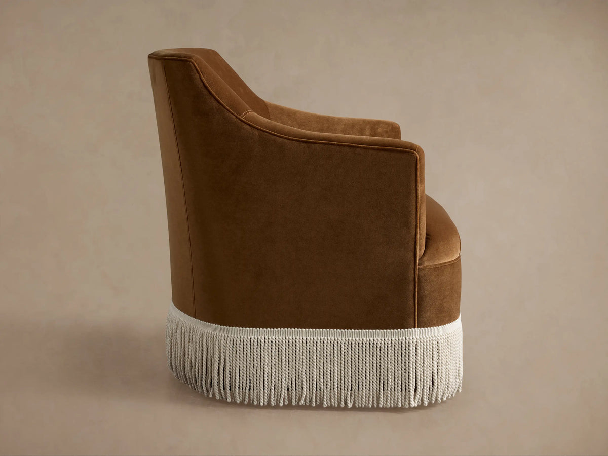 Savannah Swivel Chair with Fringe, seen from back-right, in rich brown upholstery with an off-white fringe at the bottom.