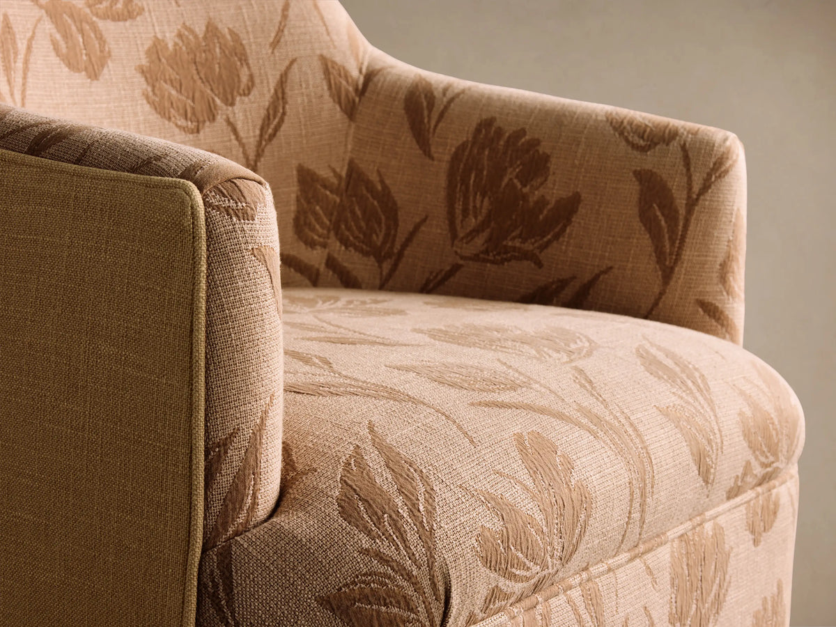 Savannah Swivel Chair, peach fabric with dark brown floral pattern, front view on wood floor.