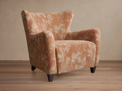 Front view of the muted peach Sasha Chair with cream floral pattern, rolled arms, and dark wood legs.
