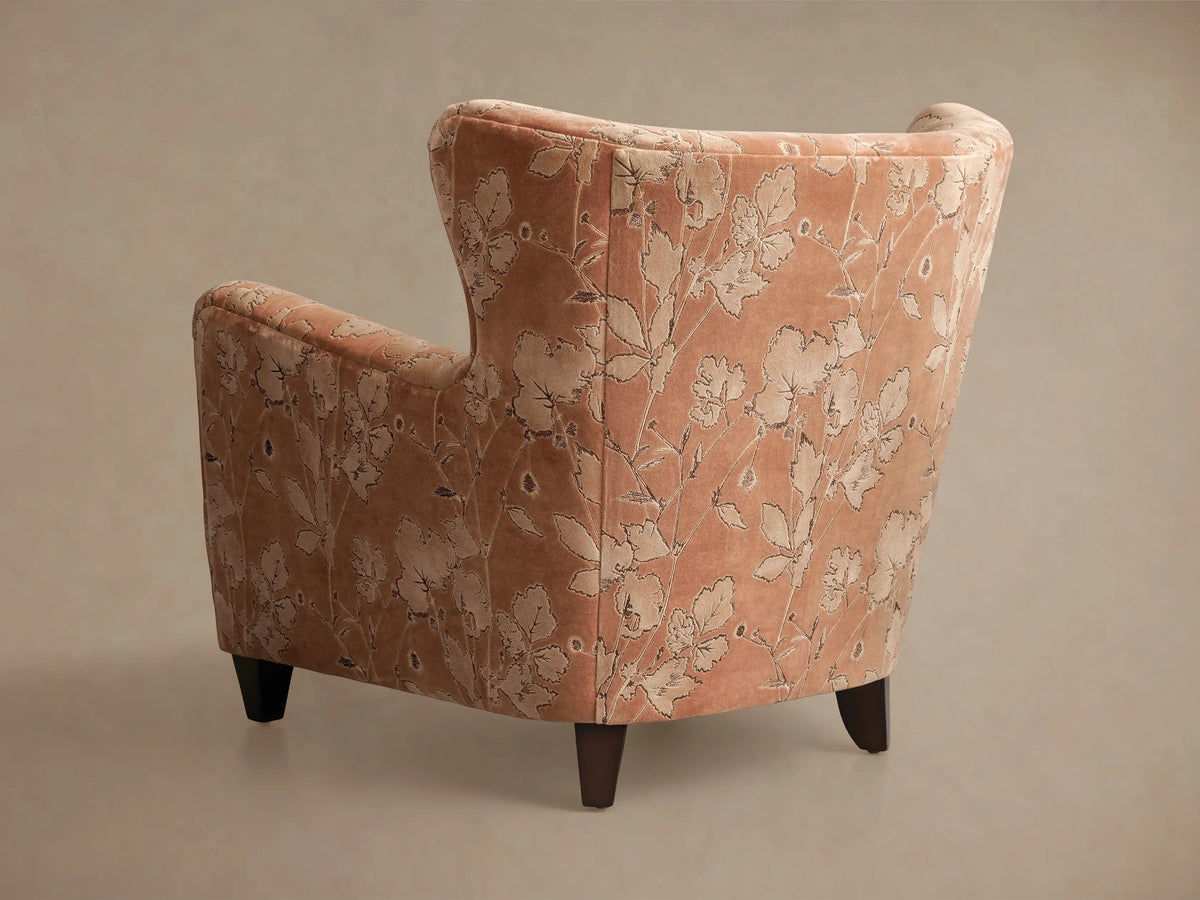 Close-up of the peach Sasha Chair armrest, featuring raised light floral patterns with dark outlines.