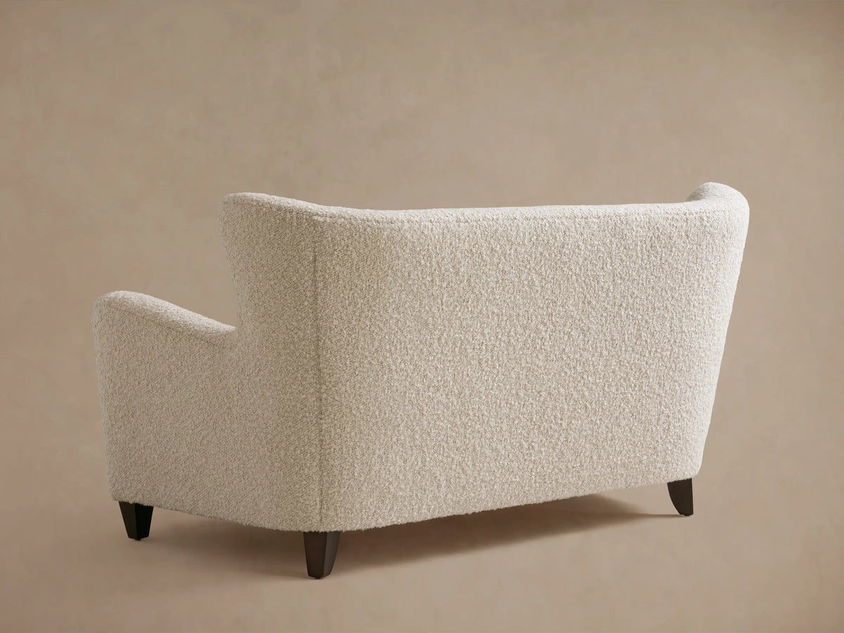 Curved armrest and backrest of the Sasha Settee in textured cream fabric, displaying a soft, inviting appearance.