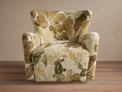 Swivel chair with high backrest and curved arms in a leaf-patterned fabric of green and brown tones on a wooden floor.