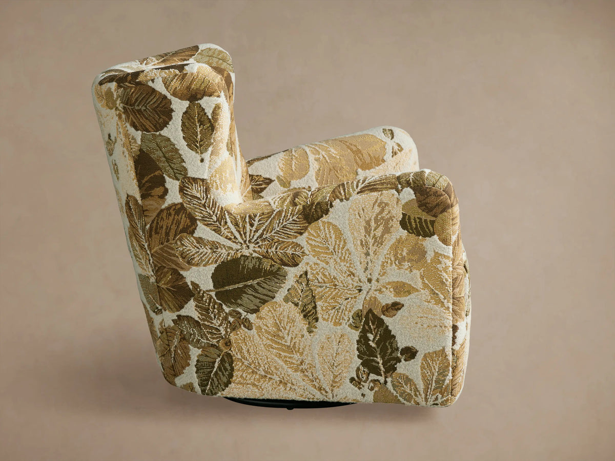Sasha Swivel Chair with a close-up of its upholstery featuring a brown and beige leaf pattern, showcasing the curved armrests and seat.