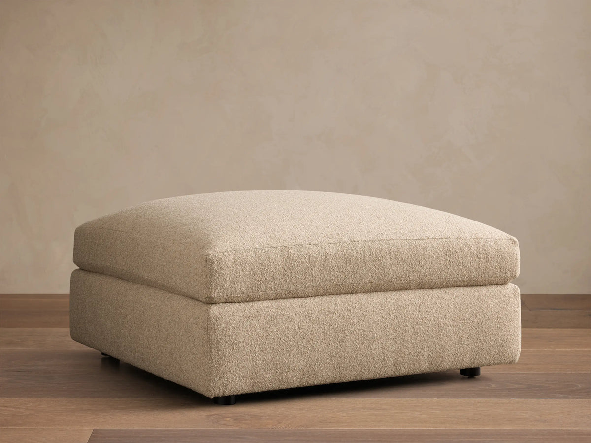 Close-up of the Beige Stiles Ottoman, highlighting its soft, nubbly textured fabric and visible corner seam.