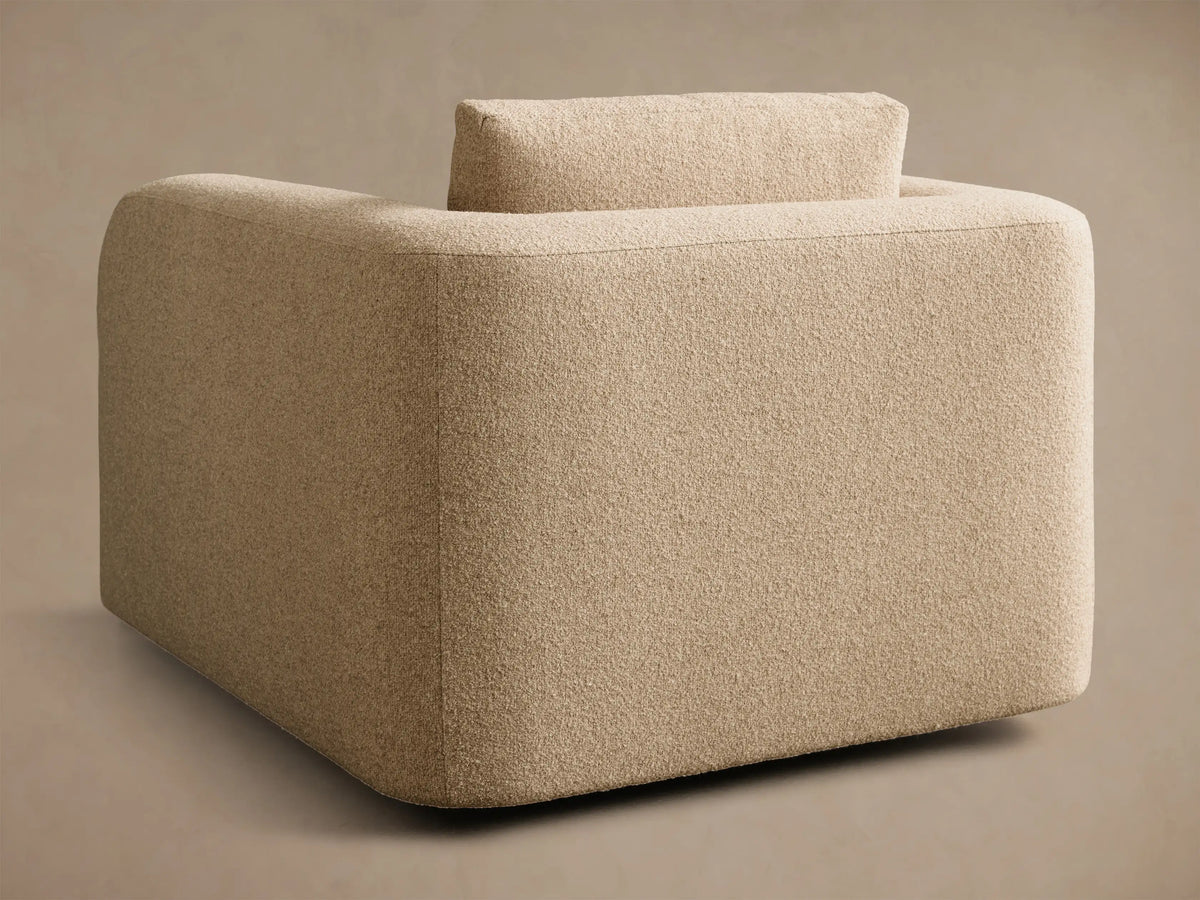 Rear-side view of a beige Stiles Swivel Chair, upholstered with rounded corners and a separate back cushion.