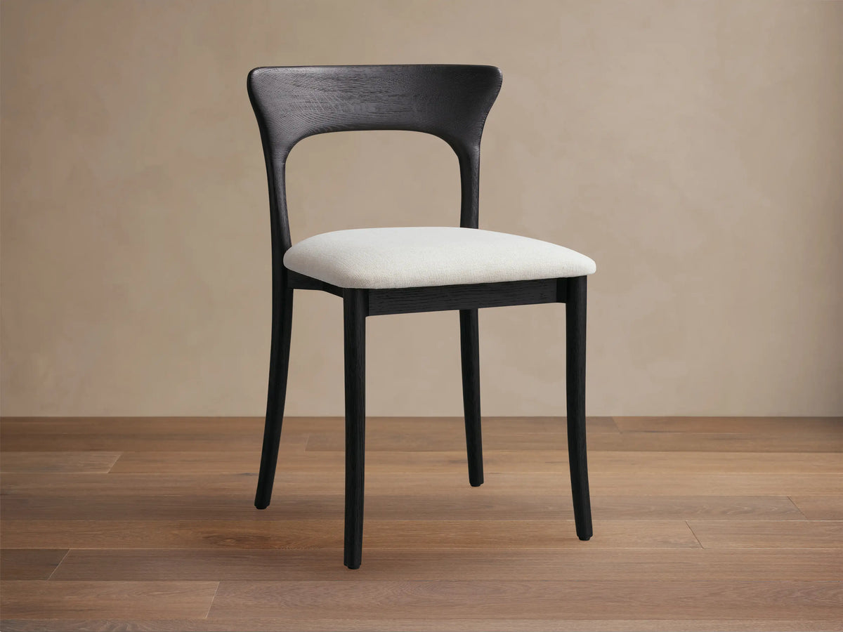 Sinclair Dining Chair: dark oak frame, curved back, cream upholstered seat, front-angled view on wood floor.