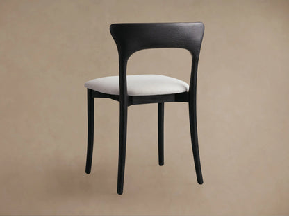 Close-up of Sinclair Dining Chair, dark curved oak backrest with visible grain, light textured fabric seat, angled view.
