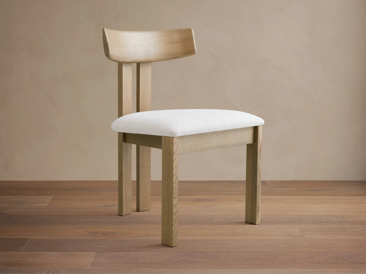 Rodin Wood Back Dining Chair: Light ash wood frame, curved back, white upholstered seat, on a wood floor.