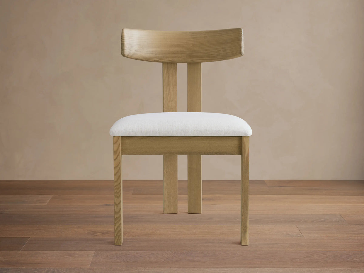 Rodin Wood Back Dining Chair: Light ash wood frame, curved back, white upholstered seat, on a wood floor.