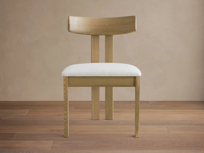 Rodin Wood Back Dining Chair: Light ash wood frame, curved back, white upholstered seat, on a wood floor.