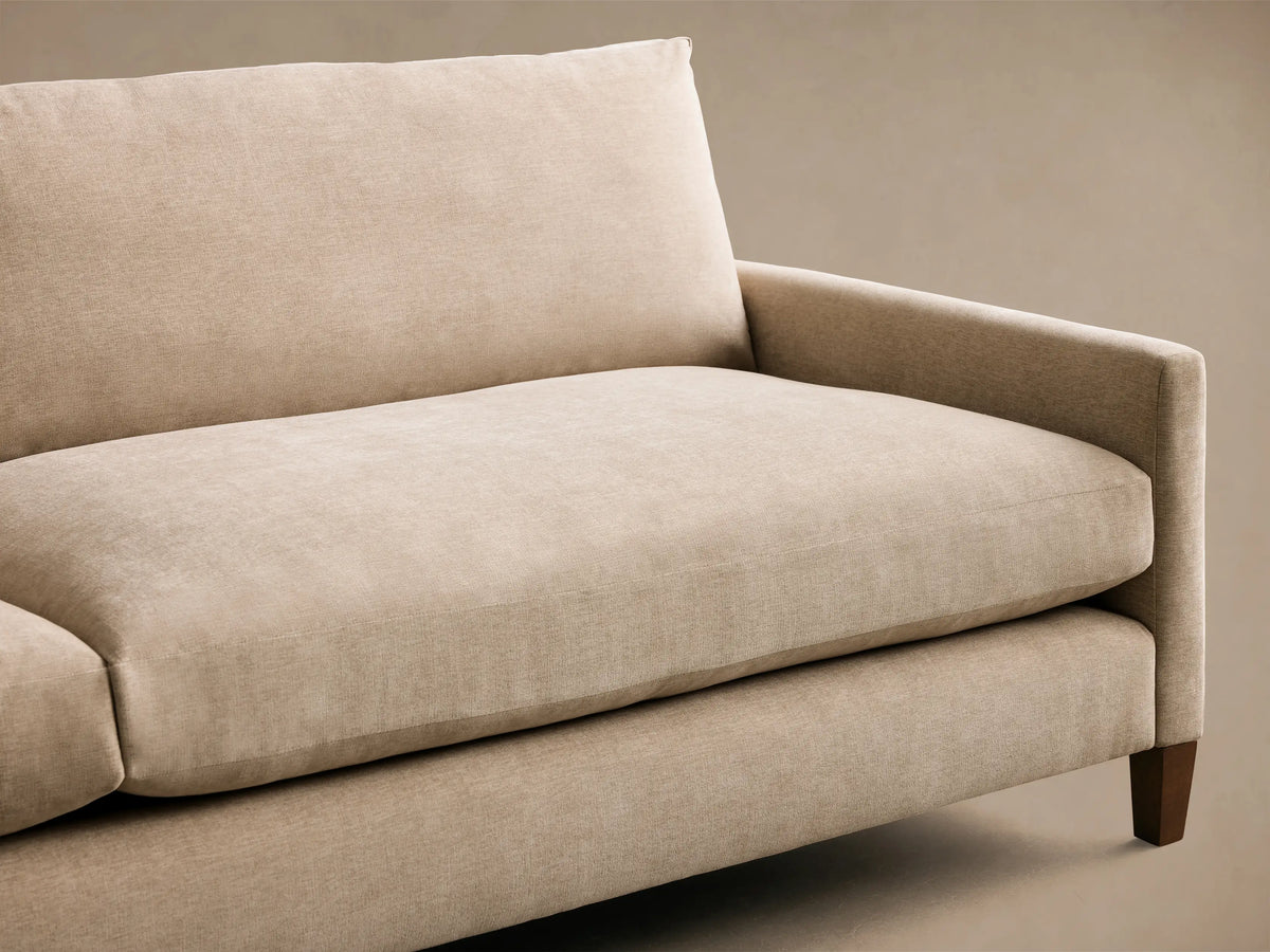 Rear view of the beige Kipton Slim Arm Elevated Sofa, showing its two back cushions and elevated mocha finish wooden legs.