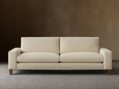 Front view of a cream Kipton Wide Arm Elevated Sofa with wide square arms, two back cushions, two seat cushions, and elevated mocha-finished legs.