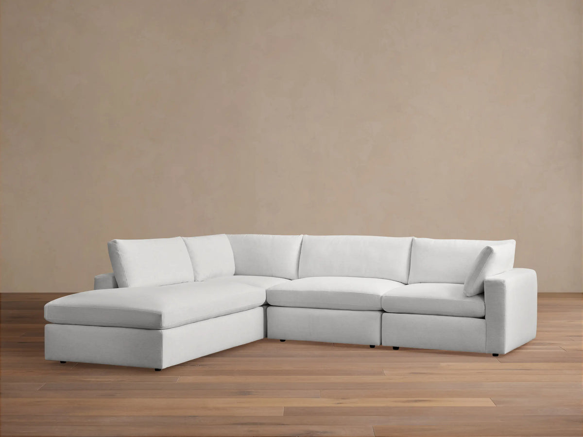Beale Two-Piece Bumper Sectional in white fabric, shown on wooden floor, with an L-shaped design and cushioned backrests.