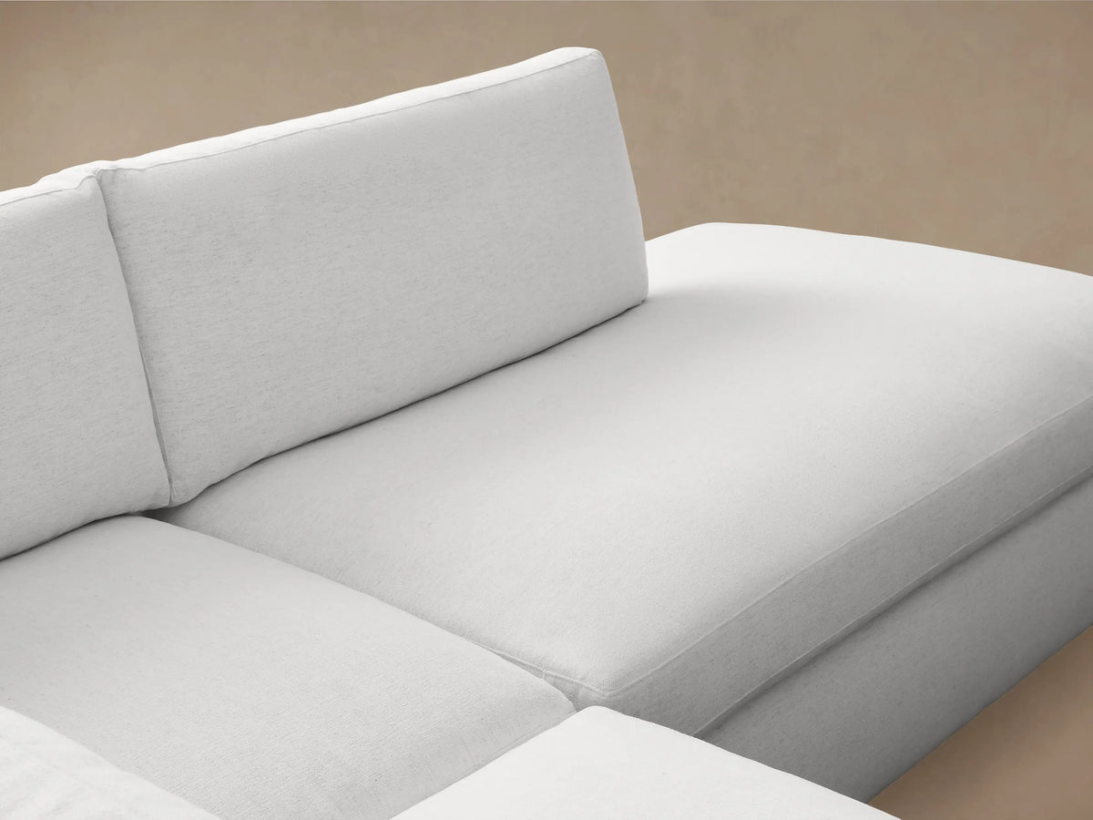 Beale Two-Piece Bumper Sectional in light gray fabric with left-arm corner seat and right-facing chaise, on wooden floor.