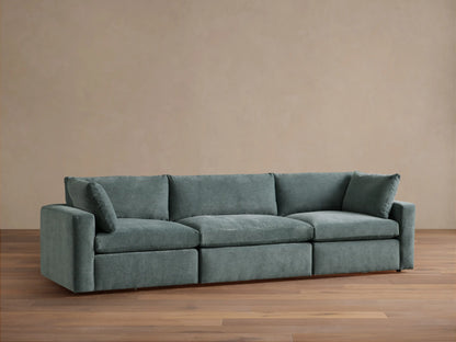 Beale Three-Piece Modular Sofa in muted blue-green fabric, plush cushions, against a light wall on a wood floor.