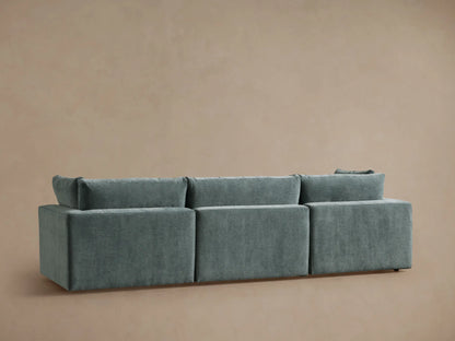 Close-up, angled view of a light teal Beale Three-Piece Modular Sofa, showing soft, velvety fabric and plush cushions.