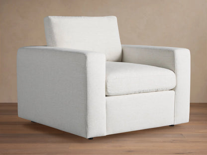 Beale Chair: a modern, off-white, boxy armchair with wide arms and textured fabric, angled on a wooden floor.