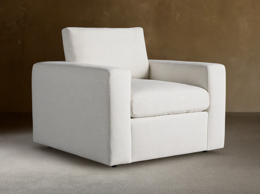 Beale Chair: a modern, off-white, boxy armchair with wide arms and textured fabric, angled on a wooden floor.