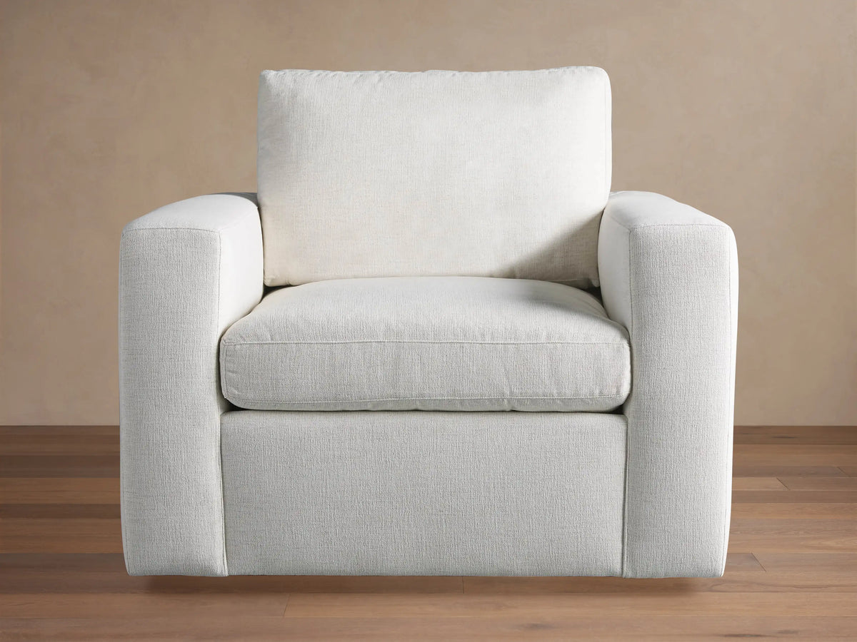 Beale Chair: a modern, off-white, boxy armchair with wide arms and textured fabric, angled on a wooden floor.