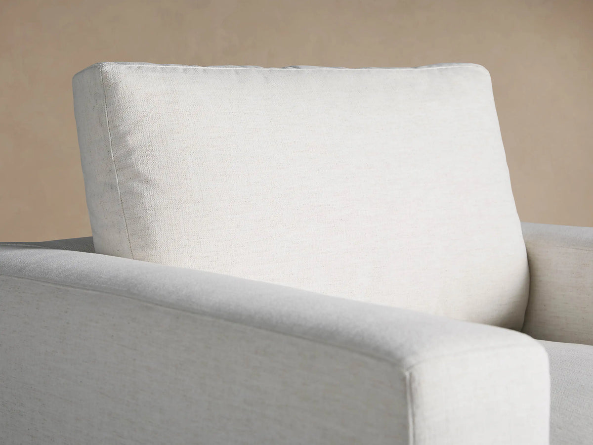 Beale Chair: a light off-white, textured armchair with thick, blocky arms and plush cushions, centered on a wood floor.