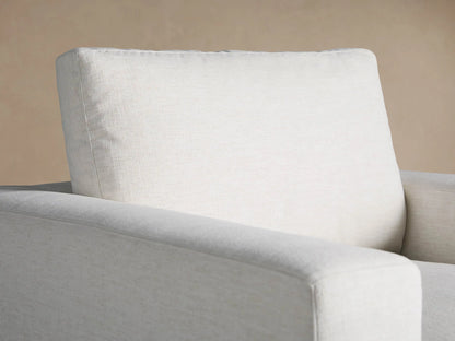 Beale Chair: a light off-white, textured armchair with thick, blocky arms and plush cushions, centered on a wood floor.