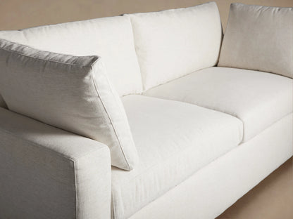 Front view of the white Beale Sofa, a relaxed two-seater with wide arms, two seat cushions, two back cushions, and two pillows.