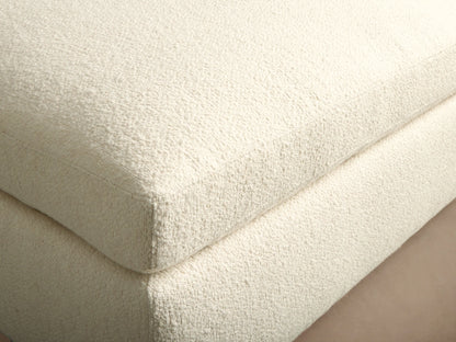Beale Ottoman, off-white textured fabric, rectangular with a soft, rounded top cushion, on a dark wood floor.